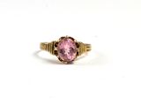 gros plan d'une bague en pierre rose sur une surface blanche