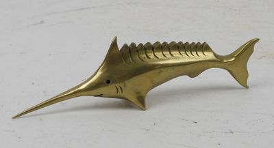 a brass fish figurine sitting on top of a white surface