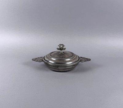 an antique silver plate with a lid on a white surface