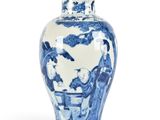 vase bleu et blanc surmonté d'un oiseau, posé sur un fond blanc