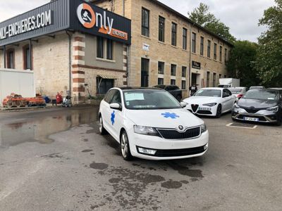 une voiture blanche garée devant un immeuble sur lequel est accrochée une enseigne lumineuse