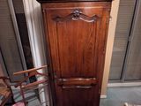 une armoire en bois posée à côté d'une chaise dans une pièce