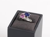 une bague dans un écrin noir, sertie d'une pierre rose et bleue