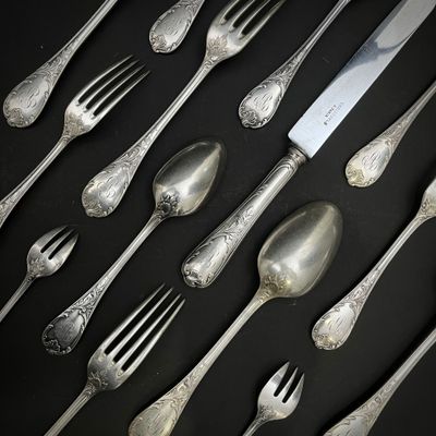 de nombreuses cuillères et fourchettes en argent posées sur une table noire
