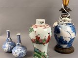 three vases and a lamp on a table with a gray background