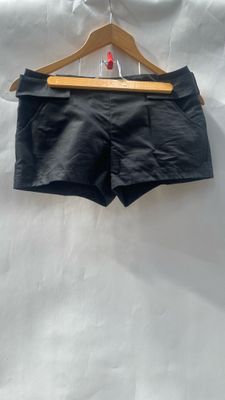 a black shorts hanging on a hanger on a white sheet