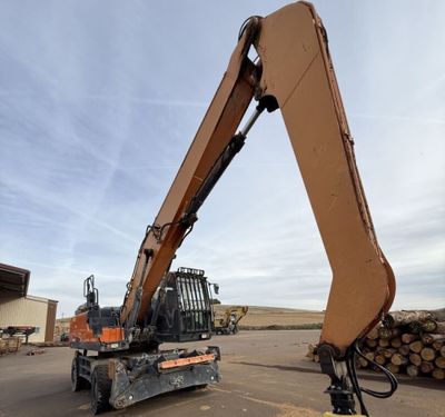 une image représentant un engin de chantier avec des grumes à l'arrière-plan