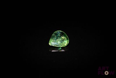 un gros plan d'un diamant vert et noir sur une surface noire