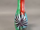 a colorful vase sitting on a table with a gray background