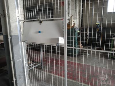 un portail métallique sur lequel est accrochée une pancarte, dans un bâtiment