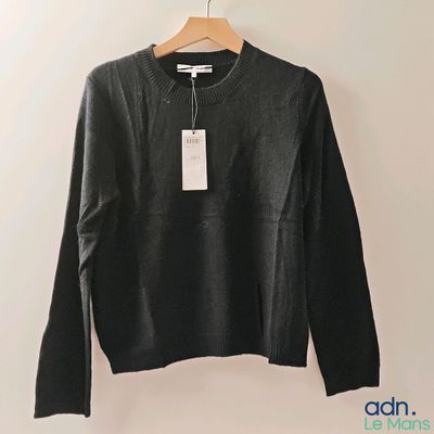 a black sweater hanging on a hanger on a wall
