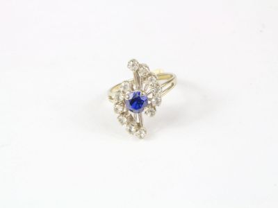 Bague en or gris centrée d'une pierre bleue facettée entre 2…