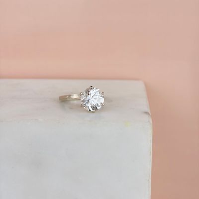 an image of a diamond ring sitting on top of a white marble block