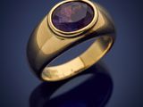 a gold ring with a purple stone in the center