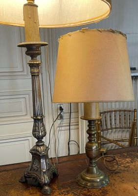 two lamps that are on a table with a chair in the background