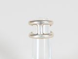 un gros plan d'une bague en argent posée sur une bouteille transparente