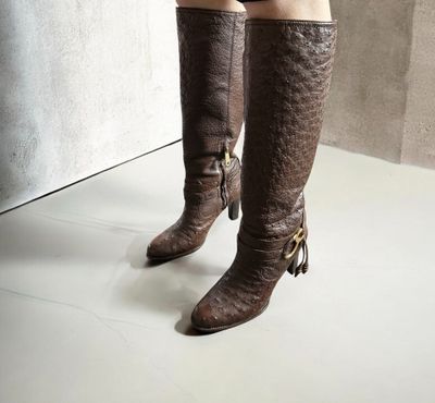 Quelqu'un porte une paire de bottes marron ornées de pompons.