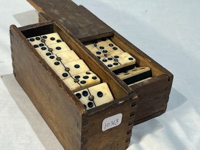 une vieille boîte en bois remplie de dominos, posée sur une table blanche