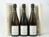 trois bouteilles de vin posées devant une boîte de vin