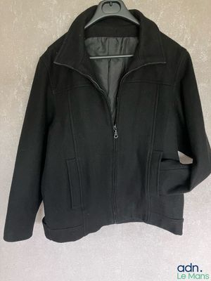 une veste noire suspendue à un cintre accroché au mur