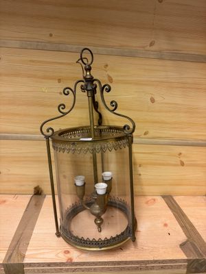 une lanterne en verre contenant une bougie, posée sur une étagère en bois