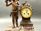 a statue of a boy holding a bird next to a clock