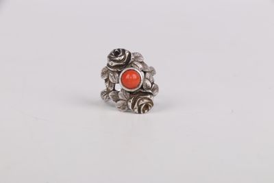 a close up of a silver ring with an orange stone