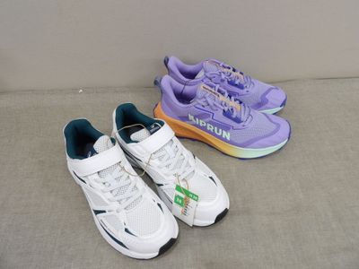 two pairs of purple and white shoes sitting on a couch