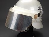 an old helmet with a metal visor on a black stand