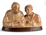 statue représentant un homme et une femme assis sur un socle en bois