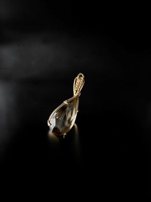 a close up of a gold pendant on a black surface