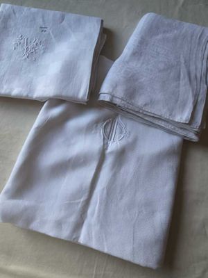 trois serviettes blanches posées sur un lit, ornées d'un monogramme
