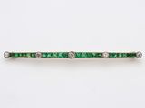 Gros plan sur une broche en forme de barre sertie d'émeraudes et de diamants