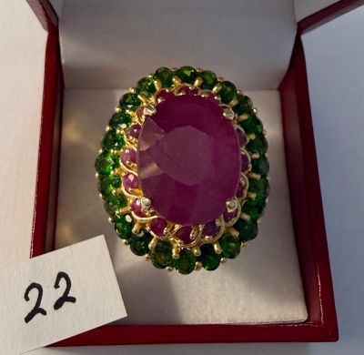 une image représentant une bague verte et rose dans une boîte rouge