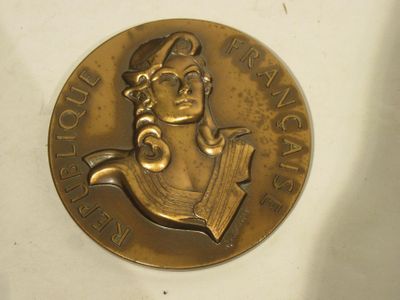a gold medal with a woman in a sailor ' s hat