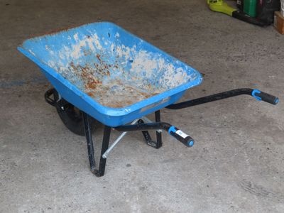 une brouette bleue dans un garage, avec une poignée noire
