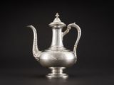 une cafetière en argent avec une anse, sur fond noir