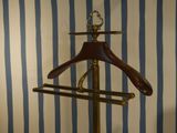 a coat rack with a wooden hanger on it in front of a striped wall