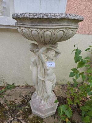 une statue représentant une femme tenant un bassin à oiseaux dans un jardin