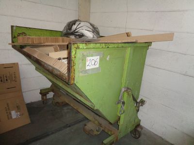 a green dumpster sitting in a room with boxes on the floor