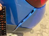 a person holding a ruler next to a blue car