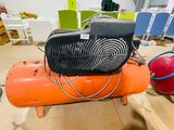 an orange air compressor sitting on top of a wooden floor next to a red ball