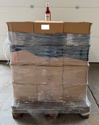 une palette remplie de cartons et une bouteille d'alcool