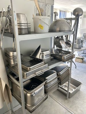 many pans and utensils on the shelves in the kitchen