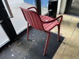 a red plastic chair sitting in front of a glass door