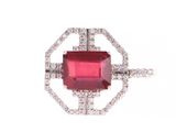 un gros plan d'une bague en pierre rouge et diamants sur fond blanc