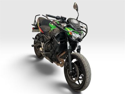 une moto noire et verte garée sur une surface blanche