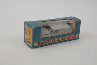 une petite voiture miniature dans une boîte posée sur une surface blanche