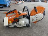 an orange and white chainsaw sitting on top of a cement floor
