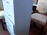 a white cabinet with drawers and a laptop on the floor